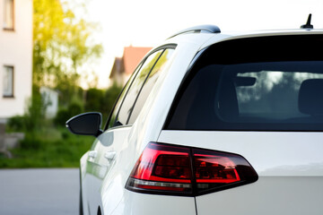Rear window of a white car parked on the street near the houses. Mockup for the car decals.