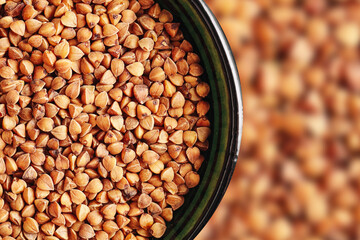 Buckwheat groats in bowl. Raw brown grains with rustic look. Traditional Eastern European food. Organic gluten-free ingredient. Healthy plant-based product with earthy texture and natural appeal.