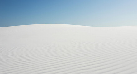 Minimalist landscape of white sand dunes under a clear blue sky.
