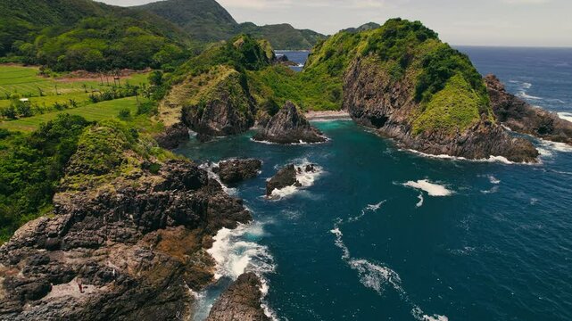 Aerial shots reveal a stunning coastal environment with dramatic rocks and lush greenery, perfect for nature projects like photography or conservation to preserve its beauty and biodiversity
