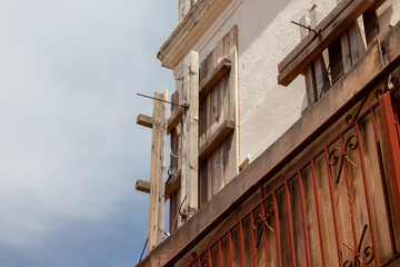 Rustic Wooden Shutters and Metal Balcony Railing on Old Building