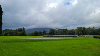 Lush Green Field with Cloud-Covered Mountains in Killarney National Park, Ireland