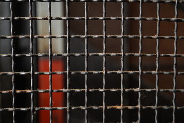 Background photograph of the close-up of a metal mesh wire grid, forming a lattice pattern with...