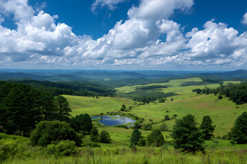 Obraz premium Scenic Vista of Rolling Green Hills and a Small Pond Under a Bright Blue Sky with Puffy White Clouds Lush Greenery and Distant Mountains