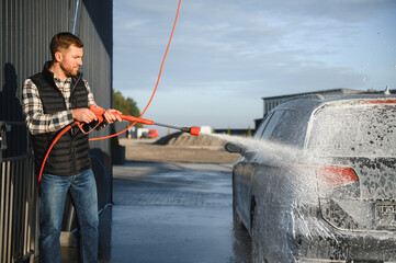 Car wash equipment. A man is washing a car at self service car wash. High pressure vehicle washer...