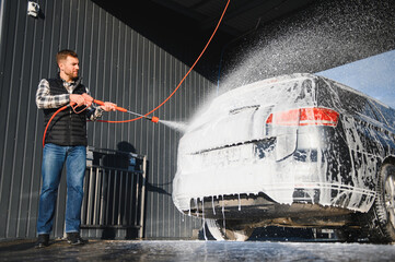 Car wash equipment. A man is washing a car at self service car wash. High pressure vehicle washer...