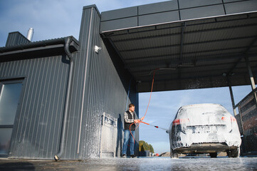 Car wash equipment. A man is washing a car at self service car wash. High pressure vehicle washer...