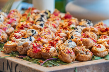 Wooden cutting board, herbs, appetizers tartletscanaps, cream cheese, olives, herbs, vibrant colors, warm brown board, natural light, indoor setting, no texts, realistic style, slightly elevated