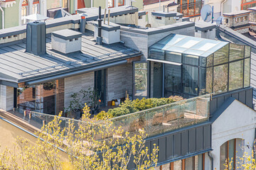 Modern two-story building with rooftop terrace and urban garden setting, featuring large windows,...
