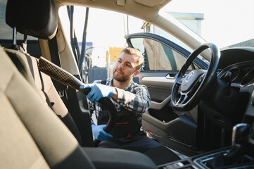 Car detailing and car wash concept. Young man, car wash worker, wearing protective rubber gloves,...