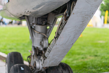 Underbelly view of a jet passenger airplane, with extended landing gear and worn metal components...