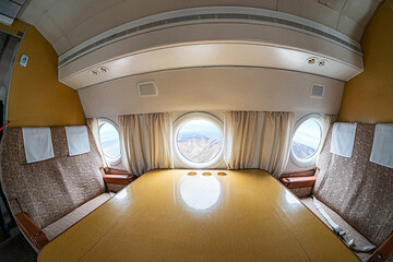 Inside view of a large passenger jet at altitude, showing windows revealing landscape, standard...
