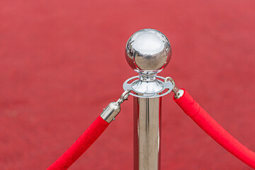 Silver podium on red carpet, gray flooring in background, indoor lighting, no people