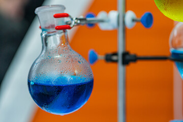 Chemistry laboratory setup with Erlenmeyer flask, reflux condenser, test tubes, graduated...