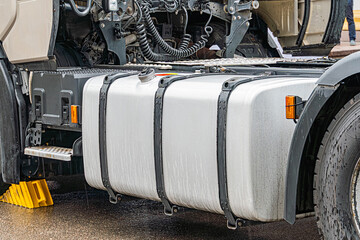 Large commercial truck parked on a wet surface, open cargo area filled with pipescylindrical...