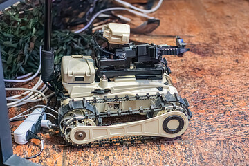 Close-up of a beige robotic tank, likely used for demining, in an indoor technical setup The tank...