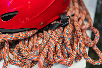 Red helmet and coiled mountaineering rope with vibrant blue and orange pattern, indoors under...