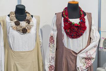 Collection of Ukrainian national dress on mannequins against light backdrop Garments include beige,...