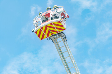 Rescue operation with fire truck ladder and two firefighters, daytime scene with clear sky