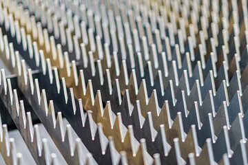 Close-up view of a parallel, uniform row of metallic spikes on a steel-like surface
