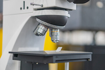 Close-up view of a white and black microscope with illumination capabilities in an industrial...