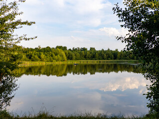 A small lake in the middle of a wooded area surrounded by trees
