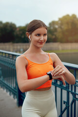 Woman Checking Smart Watch Before Running and Using Wireless Earbud. Fitness. Girl listening to...