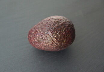 Avocado, avocado pear or alligator pear, Persea americana  - single fruit on dark grey background