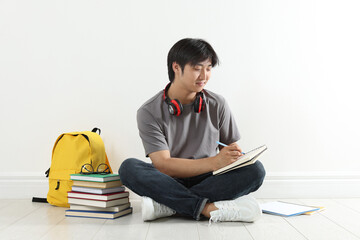 Student with notebook and pen studying on floor indoors