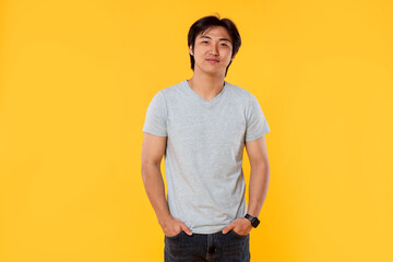Portrait of handsome Asian man on yellow background