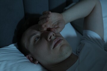 Frustrated man suffering from insomnia in bed indoors