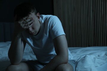 Frustrated man suffering from insomnia on bed indoors, space for text