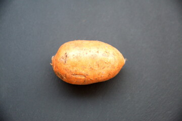 Sweet potato or sweetpotato (Ipomoea batatas), edible root, on dark grey background