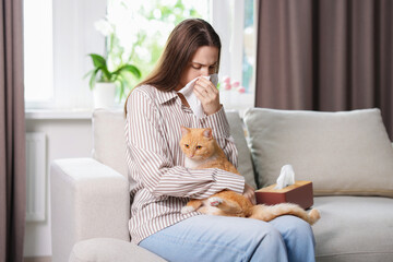 Woman suffering from allergy with her cat on sofa at home