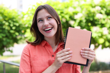 Fototapeta premium Smiling teenage girl with notepads on city street