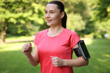 Sporty woman with armband running in park