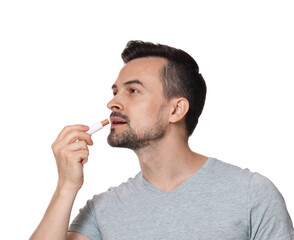 Handsome man applying lip balm onto his lips on white background
