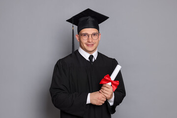 Happy student with diploma after graduation on grey background