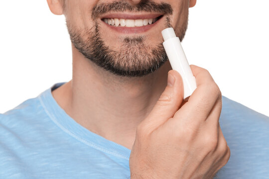 Smiling man applying lip balm onto his lips on white background, closeup
