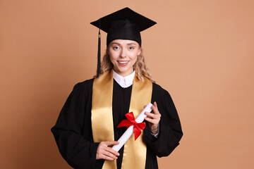 Happy student with diploma after graduation on beige background