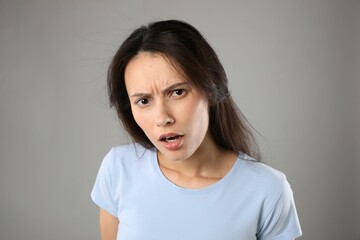 Portrait of confused woman on grey background