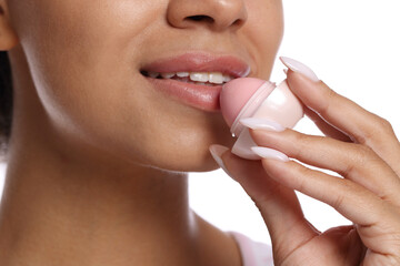 Smiling woman applying lip balm onto her lips on white background, closeup