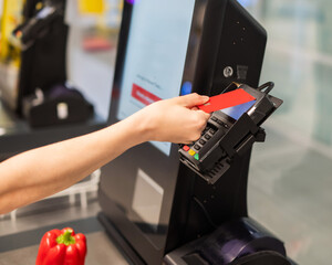 Woman paying with credit card at self-checkout. 