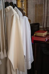 Fiew priest's surplice, liturgical vestments on a hanger, Holy Scripture in the background