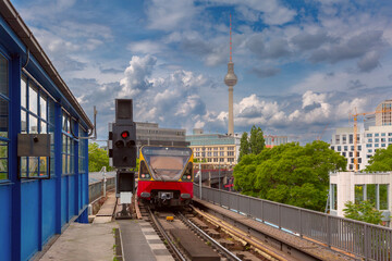 Red S-Bahn train approaching station with Berlin TV Tower in background in Berlin Germany