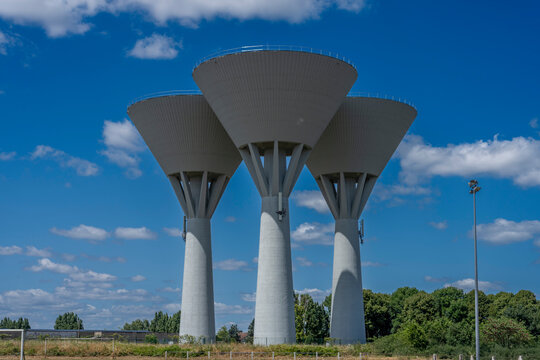 Alençon, France - 07 08 2025: Panoramic view of three white cylindrical water towers and a cloudy vlue sky in background