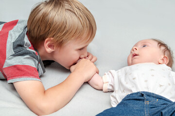Big brother lovingly kissing his little newborn infant baby sister girl.older kid meeting new sibling,lay in bed together.Family with children at home.Love,tenderness