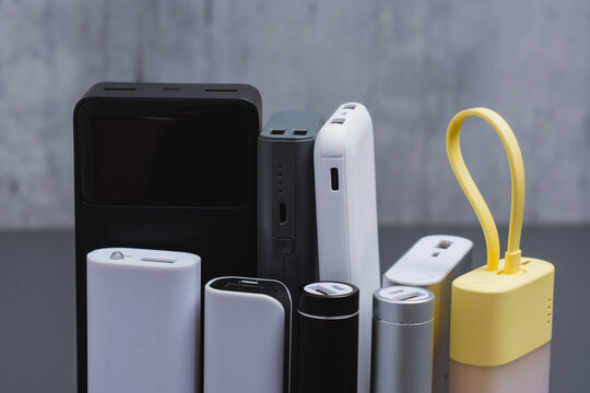 A group of power banks in various shapes, sizes, and colors on a table. Concept portable charging solutions, mobile technology, and on-the-go energy backup for smartphones and devices.