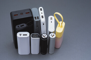 A group of power banks in various shapes, sizes, and colors on a table. Concept portable charging...