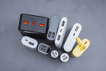 A group of power banks in various shapes, sizes, and colors on a table. Concept portable charging solutions, mobile technology, and on-the-go energy backup for smartphones and devices.
